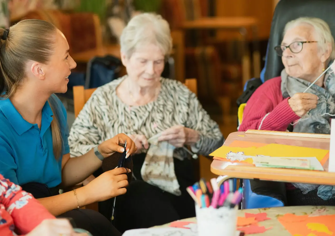 A carer chatting with residents during a craft activity in a care home
